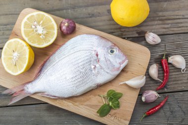 Siyah saç, balık, taze deniz ürünleri, sarımsak lezzet, yeşil sebzeler, limon, biber, domates, ahşap