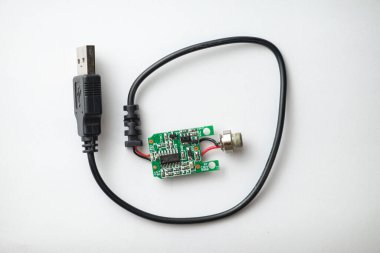 Küçük, karmaşık bir devre kartı bir USB kablosuna bağlanıyor, içinde anten var. Bu cihaz, teknoloji meraklıları ve yaratıcılar için mükemmel olan elektronik ve mühendislik füzyonunu vurgular..