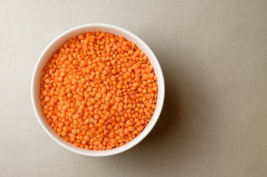 Beyaz arka planda beyaz tabakta turuncu mercimek, üst ekranda.