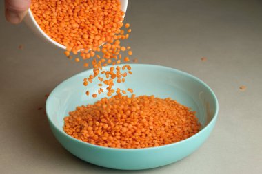 Parlak turuncu mercimekler beyaz bir kaseden çarpıcı bir turkuaz tabağa dönüşüyor. Mutfak sahnesi yemek pişirmenin güzelliğini ve sağlıklı yemekler hazırlamanın neşesini yakalar..