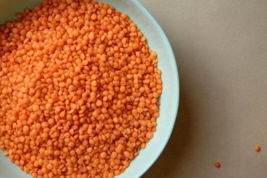 Güzel bir turuncu mercimek koleksiyonu mavi bir kâseyi doldurur ve canlı bir görüntü yaratır. Mercimekler biraz dağınık, kompozisyona enerji katıyor..