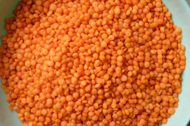 Büyük bir kase parlak turuncu mercimeklerle dolup taşar ve zengin renklerini sergiler. Bu darbeler lezzetli, sağlıklı bir yemek vadediyor, pişirilmeyi ve eğlenilmeyi bekliyor..