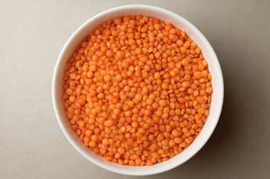 Parlak turuncu mercimeklerle dolu bir kase nötr bir yüzeyde oturur ve aşçıları sağlıklı yemekler yapmaya davet eder. Bu mercimek yemeklere besin, tat ve canlı renkler vaat ediyor..