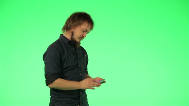 Chico joven con su teléfono en pantalla verde — Vídeo de stock