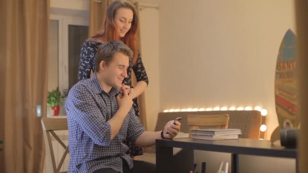 Paar jonge mensen lachen en kijken naar mobiele telefoon — Stockvideo