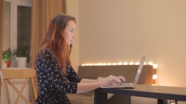 Jovem mulher trabalhando em um laptop em casa — Vídeo de Stock