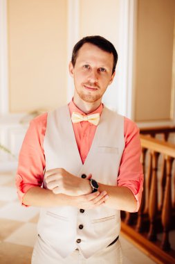 Stylish and handsome groom in waistcoat preparing to the wedding day.