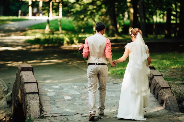 Novia y novio en el día de la boda caminando al aire libre en la naturaleza verde . — Foto de Stock