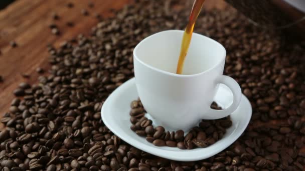 Versare il caffè in tazza circondato da chicchi di caffè — Video Stock