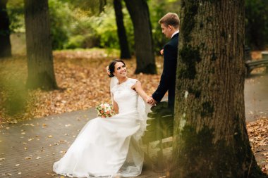 Gelin ve damat sonbahar parkta bankta oturmuş