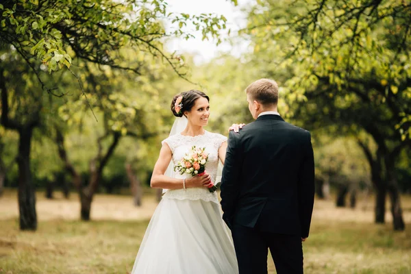 Элегантный стильный жених обнимается со своей счастливой невестой в парке — стоковое фото