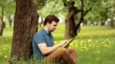 Çok gülümseyen hipster adam güneşli bir günde onun tablet PC'yi kullanma