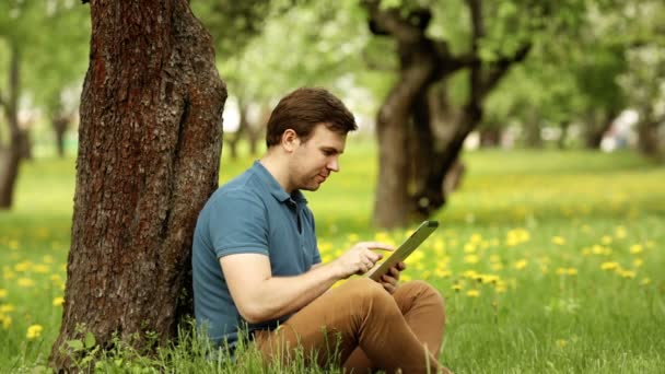 Knappe hipster man met zijn tablet pc op een zonnige dag — Stockvideo