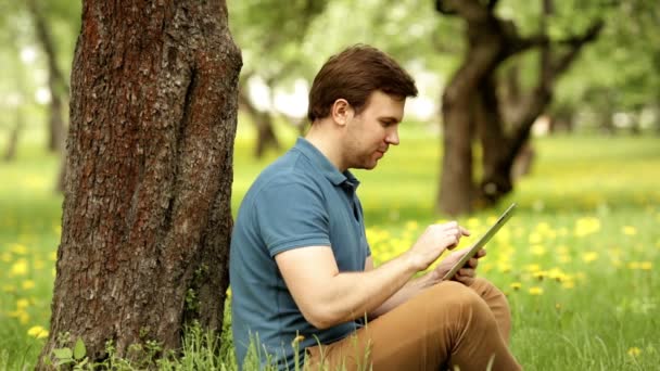 Vonzó csípő ember, egy napsütéses napon a tábla-pc használata — Stock videók