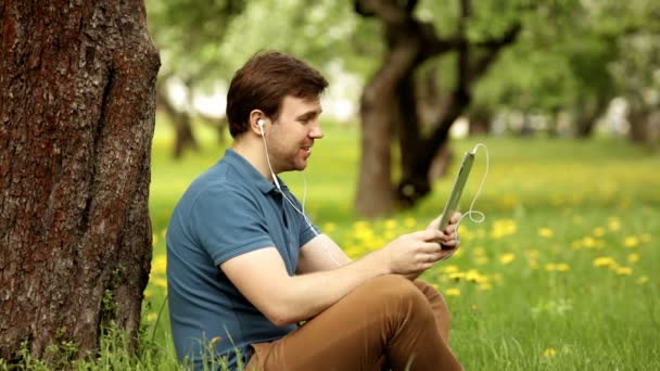 Bonito hipster conversa homem usando seu tablet pc em um dia ensolarado — Vídeo de Stock