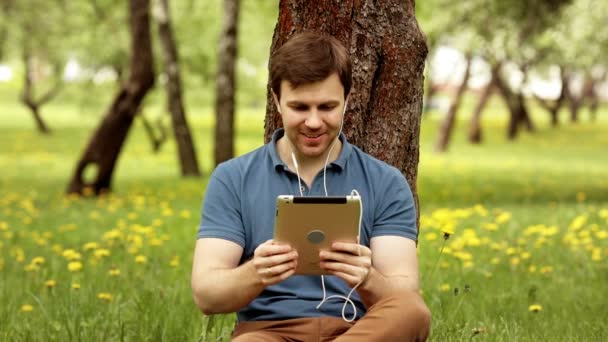 Schöner Hipster-Mann spricht an einem sonnigen Tag mit seinem Tablet-PC — Stockvideo