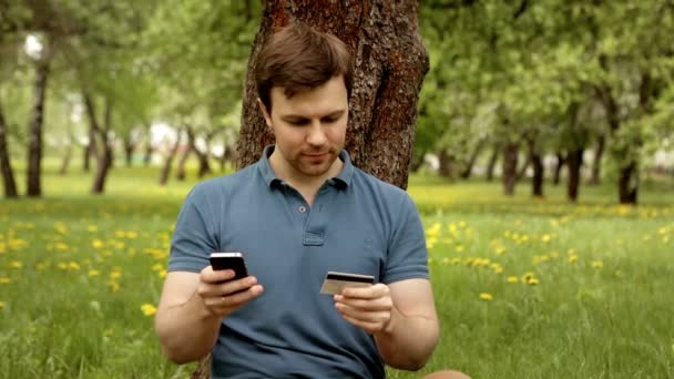 Красивый мужчина с кредитной картой и телефоном во время покупок через интернет — стоковое видео