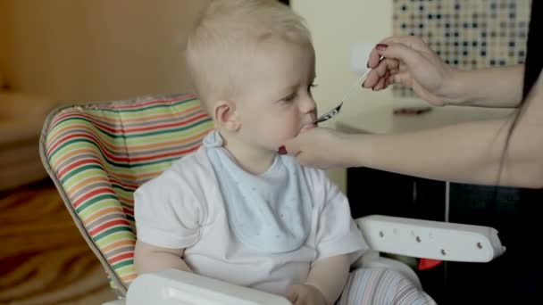 Мать кормит мальчика дома — стоковое видео