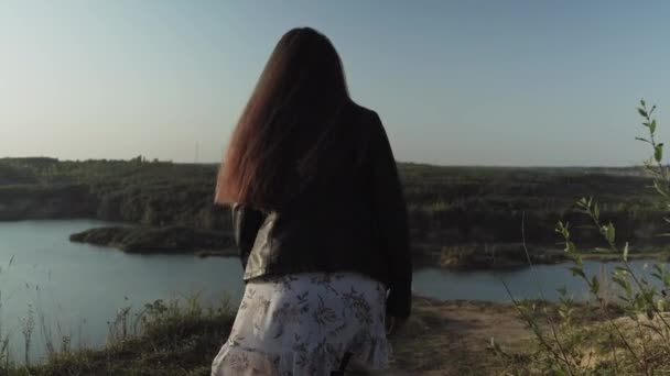 Mujer caminando con el lago al fondo. Observando el atardecer con hermoso paisaje. — Vídeo de stock