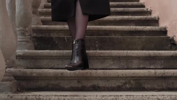 Stílusos, fekete kabátos nő sétál le a lépcsőn. Romantikus női szabadban. — Stock videók