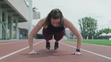 Şınav çeken bir bayan sporcu. Koşu parkurunda egzersiz yapan motive kız
