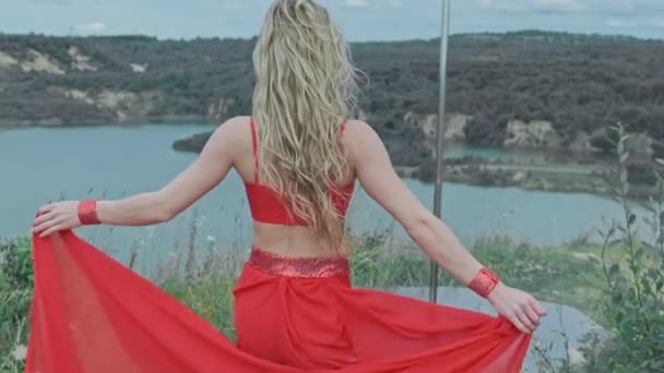 Jovem de vestido vermelho ir ao pólo. Céu e lago ao fundo. 4K, UHD — Vídeo de Stock