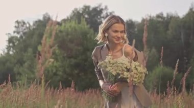 Güzel bir kadın çimenlerle eğleniyor. Çiçek buketi olan bir kadın.