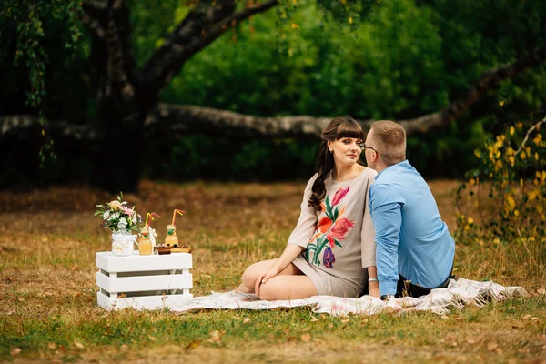 Embarazada hermosa mujer con su apuesto marido dulcemente descansando al aire libre en el otoño en el picnic . — Foto de Stock