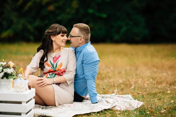 Těhotná krásná žena s manželem krásný sladce odpočívat venku na podzim na piknik. — Stock fotografie