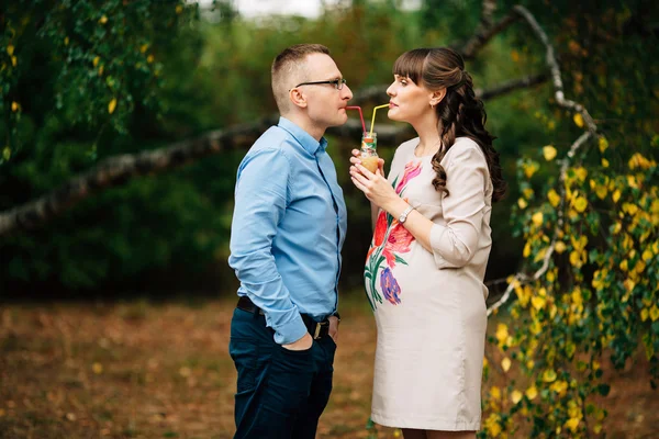 Härlig ung vacker gravid kvinna och hennes stilig man dricka juice. — Stockfoto