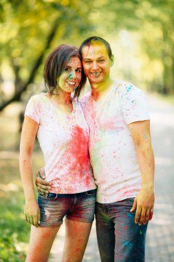 Genç ve güzel, hippi çift kamera holi renkli Festivali renkli boya tozu ile parkta mutlu gülüyorsun.