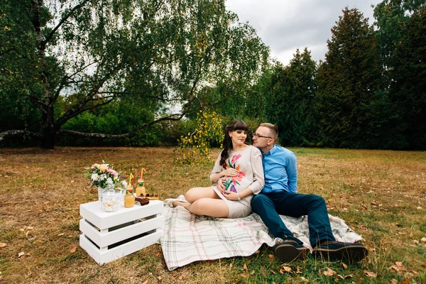 Embarazada hermosa mujer con su apuesto marido dulcemente descansando al aire libre en el otoño en el picnic . —  Fotos de Stock