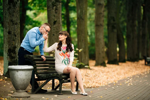 秋の公園のベンチに座ってで外リラックスした美しいの妊娠しているスタイリッシュなカップル. — ストック写真