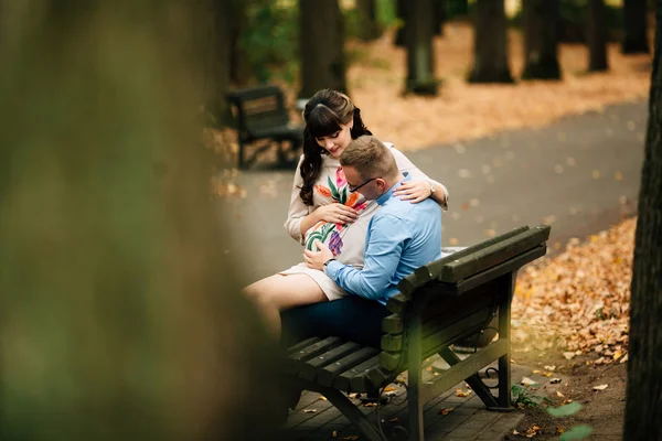 Hermosa pareja embarazada elegante relajarse al aire libre en el parque de otoño sentado en el banco . —  Fotos de Stock