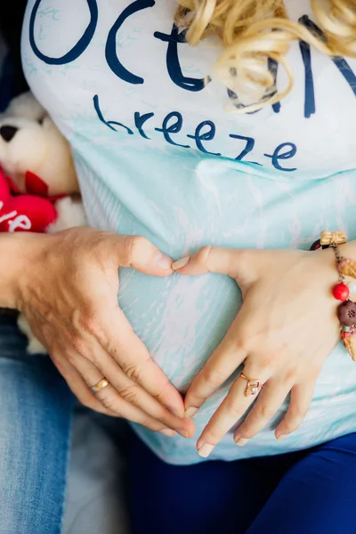 Föräldrar händer att göra hjärtat på magen på den gravida modern — Stockfoto