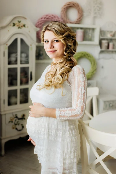 Vackra gravid kvinna smeka hennes mage i vita rummet. — Stockfoto