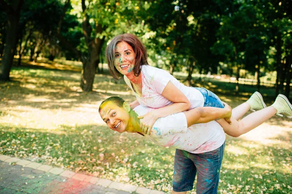 Joven y hermosa pareja hipster jugando en el parque en el festival de color holi con polvo de pintura de color . — Foto de Stock