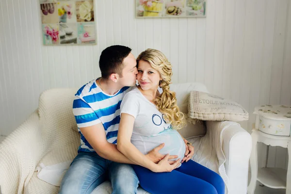 Casal com mulher grávida relaxando no sofá juntos. Imagens Royalty-Free