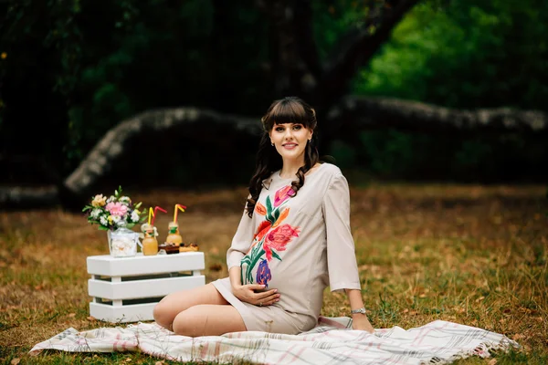 Beautiful pregnant woman holds belly in autumn park. — Stockfoto