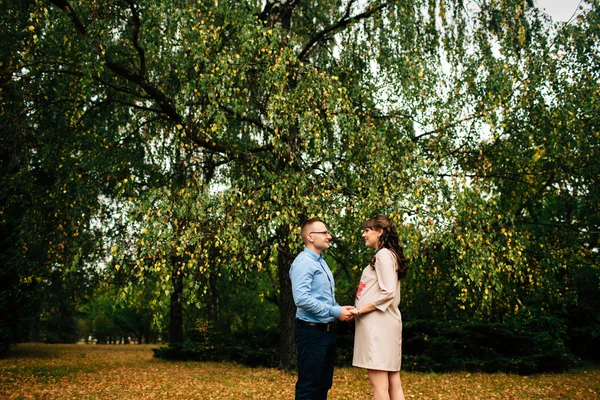 Vackra gravid kvinna och hennes stilig man härlig avkopplande på naturen, ha picknick i höst park. — Stockfoto