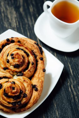 Tea and homemade bakery with chocolate on dark wooden table.