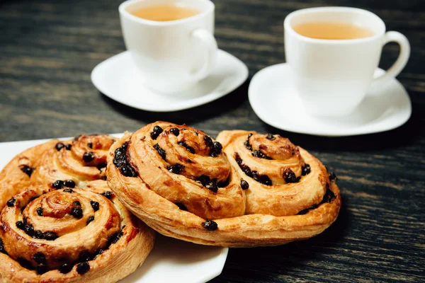 Tasty pretzels and two cups of tea on dark wooden table — Stock Photo, Image