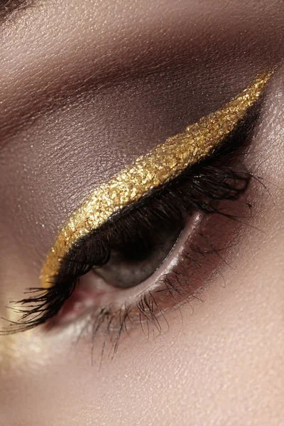 Beautiful macro shot of female eye with ceremonial makeup. Perfect shape of eyebrows, eyeliner and pretty gold line on eyelid. Cosmetics and make-up. Closeup macro shot of fashion sparcle visage — Stock Photo, Image