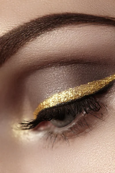 Beautiful macro shot of female eye with ceremonial makeup. Perfect shape of eyebrows, eyeliner and pretty gold line on eyelid. Cosmetics and make-up. Closeup macro shot of fashion sparcle visage — Stock Photo, Image