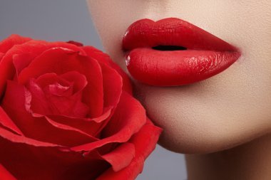 Yakın çekim güzel kadın dudakları parlak lipgloss makyaj ile. Mükemmel temiz cilt, seksi kırmızı dudak makyaj. Kırmızı gül çiçek güzel sima portre. Son saatlerinde yanında bulunanlar ve kozmetik