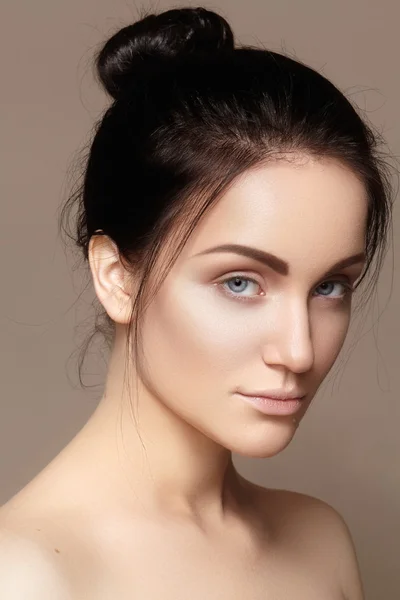 Schöne junge Frau mit sauberem Gesicht, glänzender Haut, modischem natürlichen Make-up, perfekten Augenbrauen. Niedliche Dutt-Frisur. Wellness-Porträt, Naturkosmetik, gesundes frisches Aussehen — Stockfoto