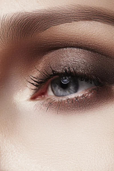 Hermoso macroplano de ojo femenino con maquillaje ahumado clásico. Forma perfecta de cejas, sombras marrones y pestañas largas. Cosméticos y maquillaje. Primer plano macro disparo de moda ojos ahumados visage — Foto de Stock