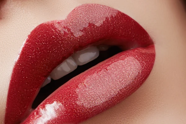 Primer plano de labios femeninos con maquillaje brillante. Macro de cara de mujer. Maquillaje de labios de moda con brillo rojo. Maquillaje de brillo de labios rojo en labios femeninos completos — Foto de Stock