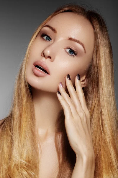 Hermosa mujer joven con la piel limpia, hermoso cabello liso brillante, maquillaje de moda. Maquillaje de glamour, cejas de forma perfecta. Retrato sexy rubio. Hermoso peinado suave. Esmalte de uñas brillante — Foto de Stock