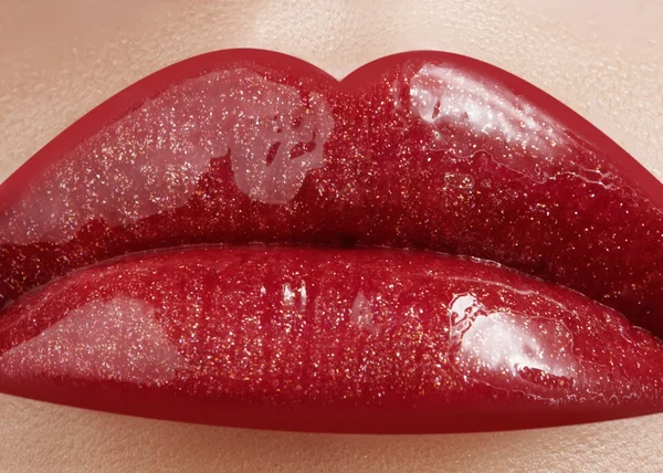 Primer plano de labios femeninos con maquillaje brillante. Macro de cara de mujer. Maquillaje de labios de moda con brillo rojo. Maquillaje de brillo de labios rojo en labios femeninos completos —  Fotos de Stock